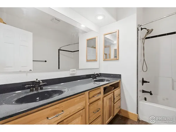 a bathroom with a granite countertop sink a mirror a bathtub and shower