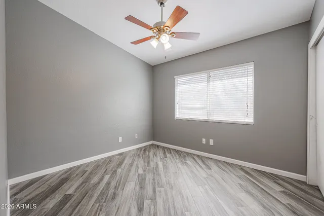 a view of an empty room with window and wooden floor