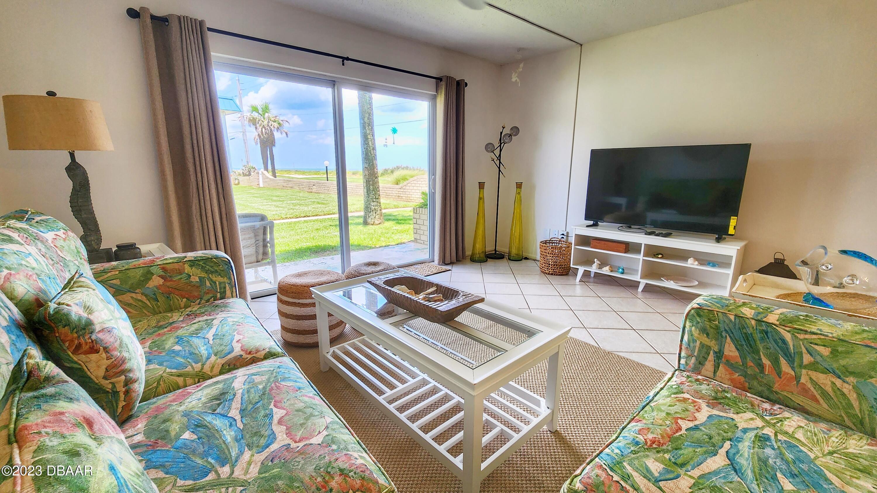 2750 Ocean Shore Boulevard, Unit 8 Ormond Beach, FL 32176 - Photo 26 of 60 a living room with furniture and a flat screen tv