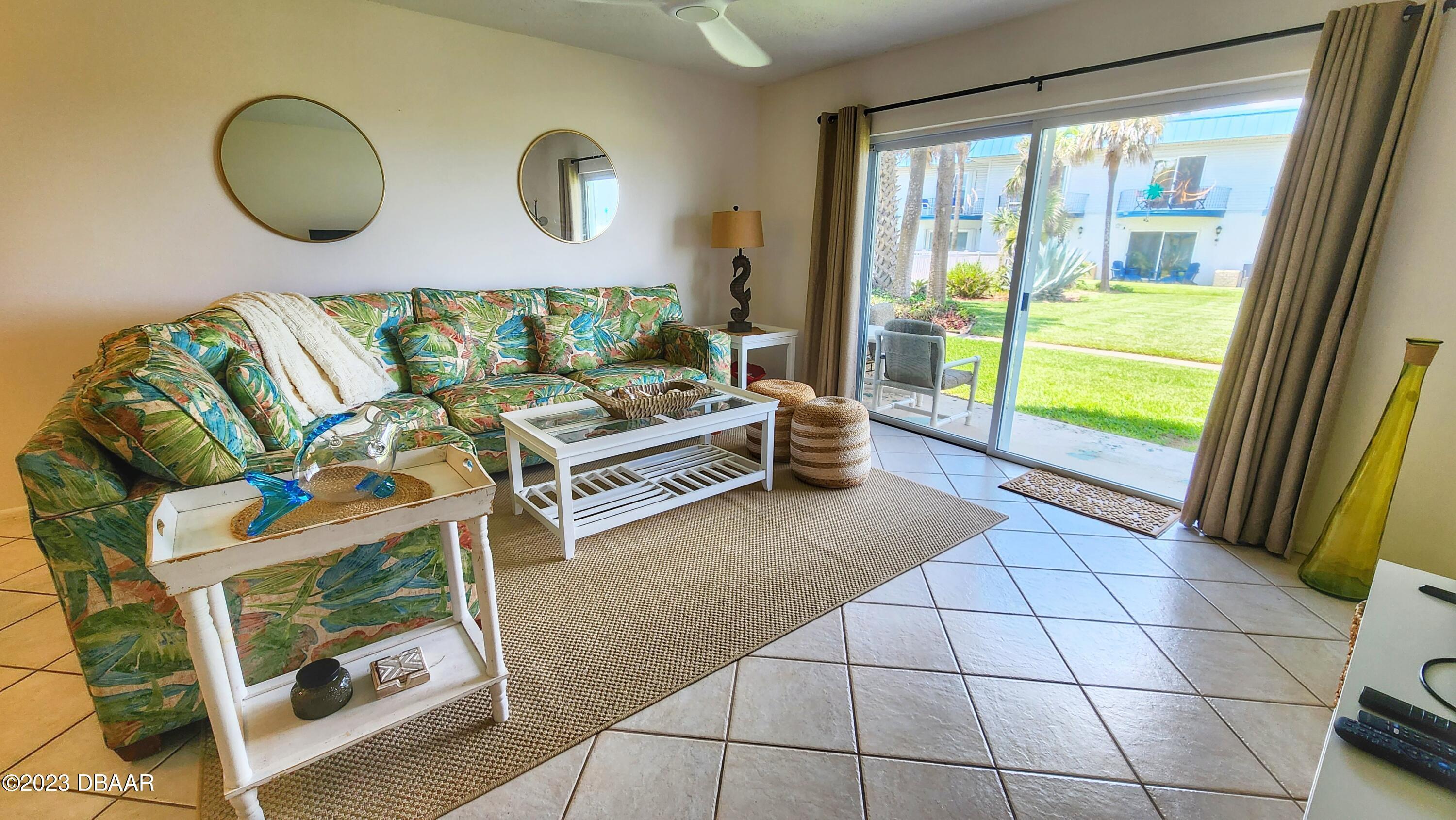 2750 Ocean Shore Boulevard, Unit 8 Ormond Beach, FL 32176 - Photo 42 of 60 a living room with furniture and a floor to ceiling window