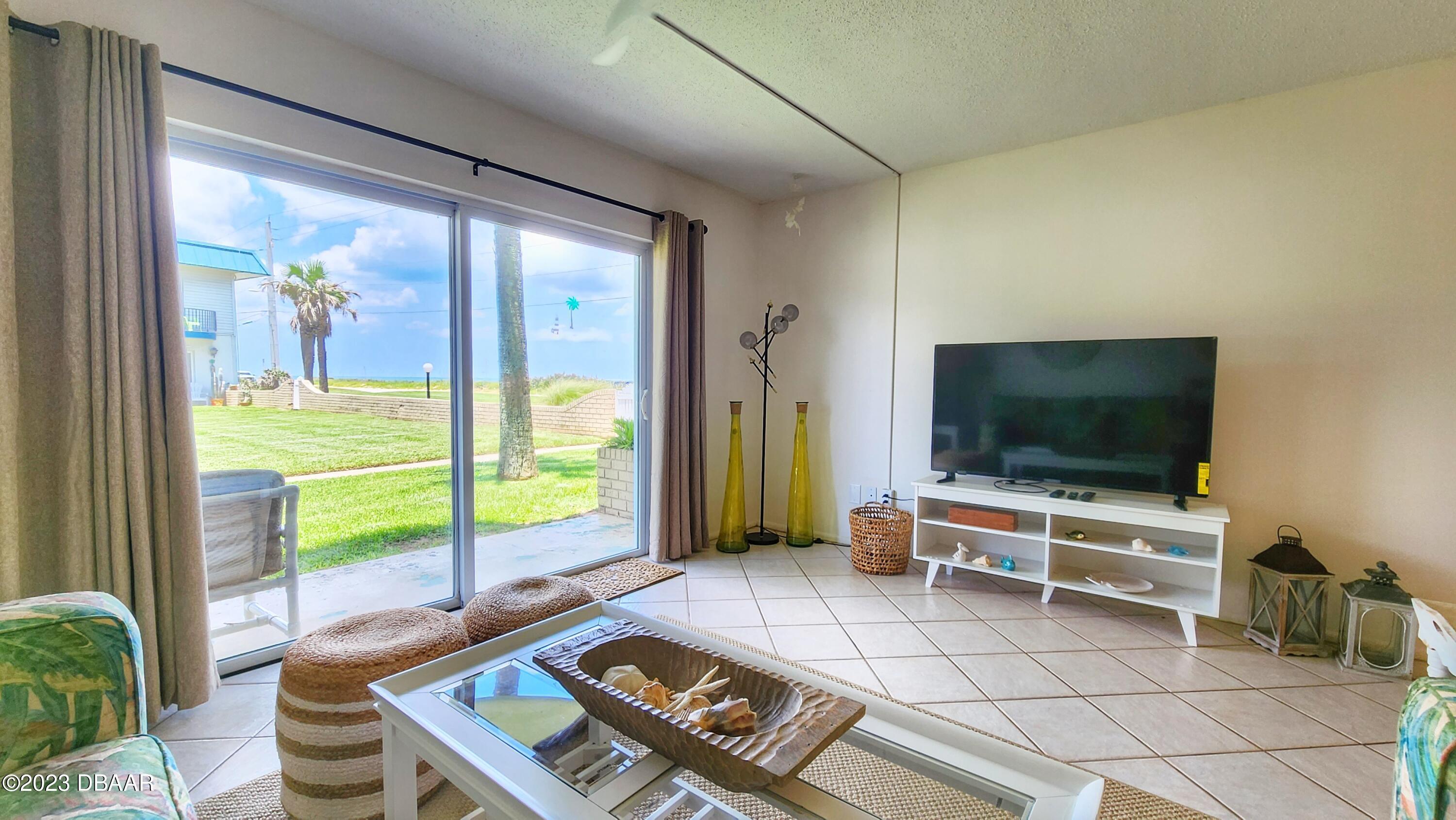 2750 Ocean Shore Boulevard, Unit 8 Ormond Beach, FL 32176 - Photo 43 of 60 a living room with furniture and a flat screen tv