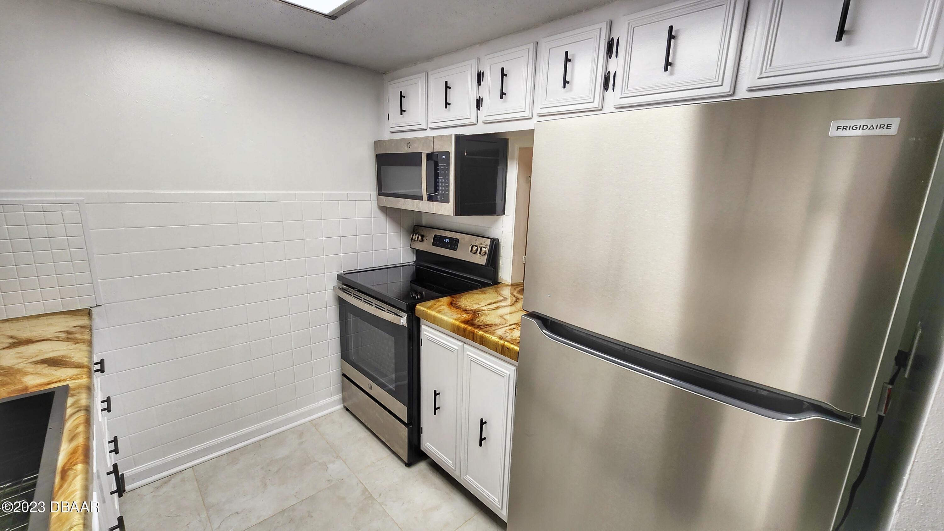 2750 Ocean Shore Boulevard, Unit 8 Ormond Beach, FL 32176 - Photo 47 of 60 a utility room with wooden floor and cabinets