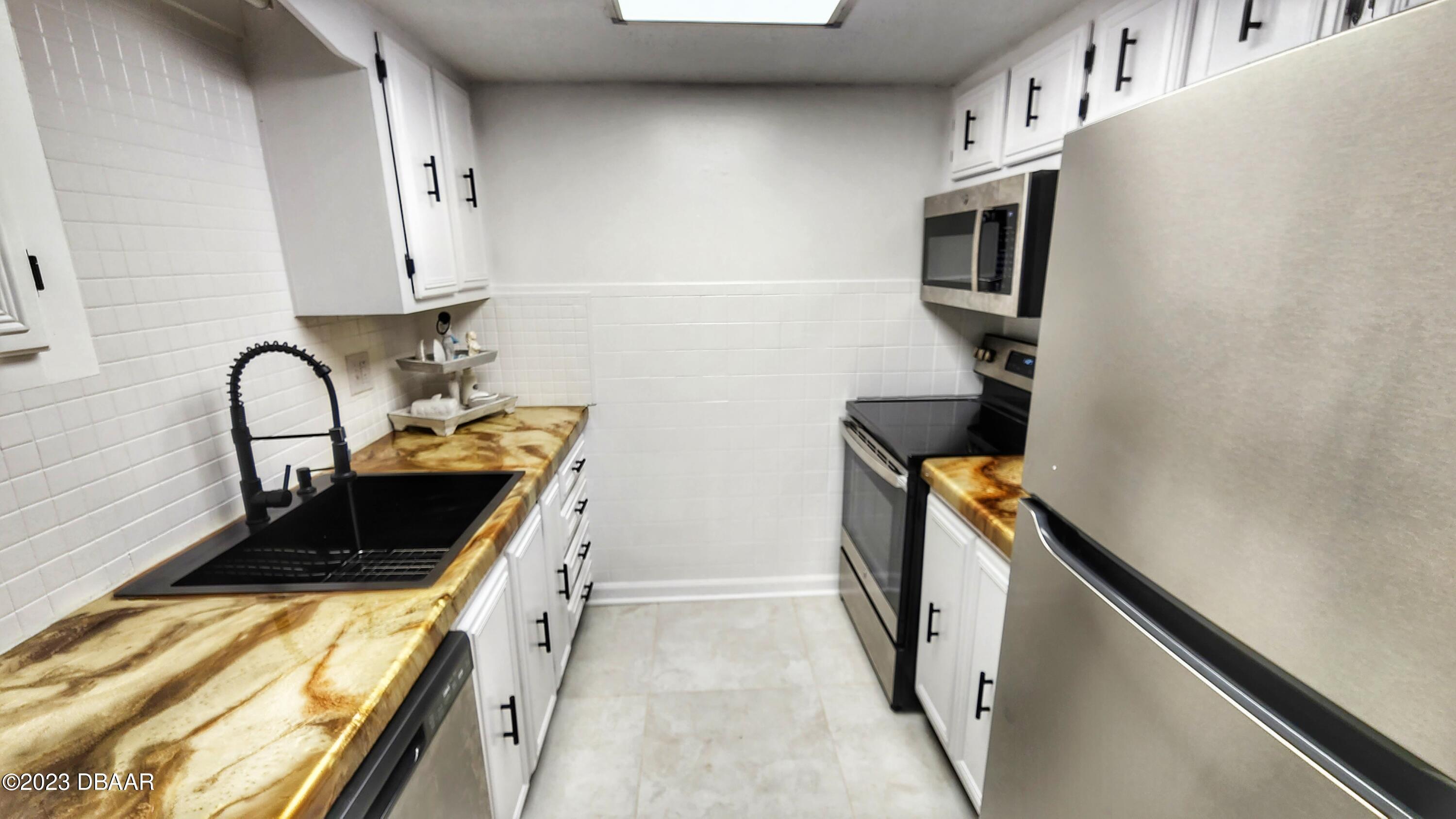 2750 Ocean Shore Boulevard, Unit 8 Ormond Beach, FL 32176 - Photo 48 of 60 a kitchen with a stove and a refrigerator