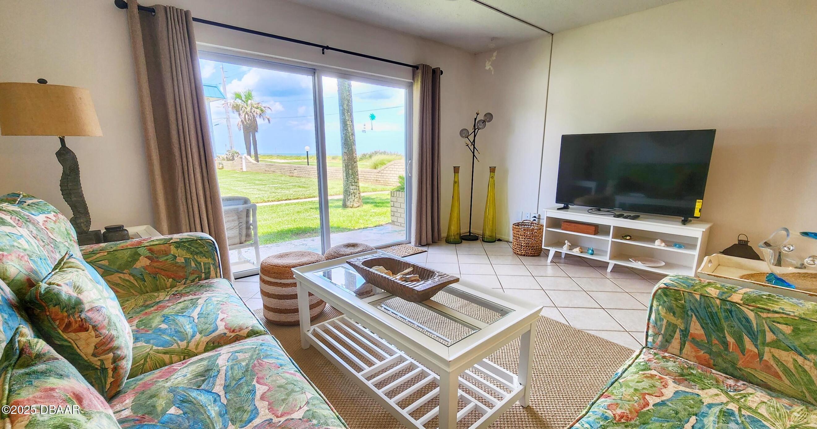 2750 Ocean Shore Boulevard, Unit 8 Ormond Beach, FL 32176 - Photo 10 of 60 a living room with furniture and a flat screen tv