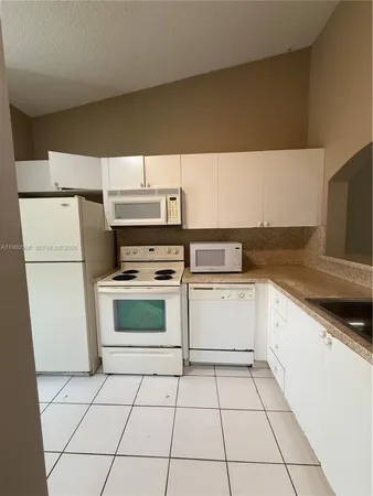 a view of a refrigerator in kitchen and an empty room with windows