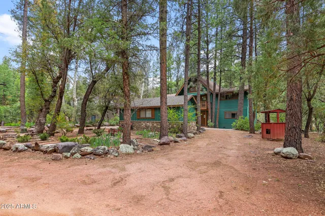 a view of a white house with a yard plants and large tree