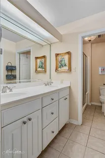 a spacious bathroom with double sink a two mirror a window and a shower