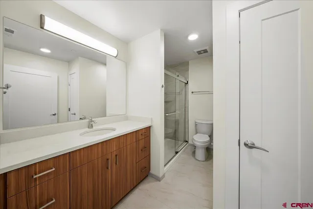 a spacious bathroom with a granite countertop toilet a sink and a mirror