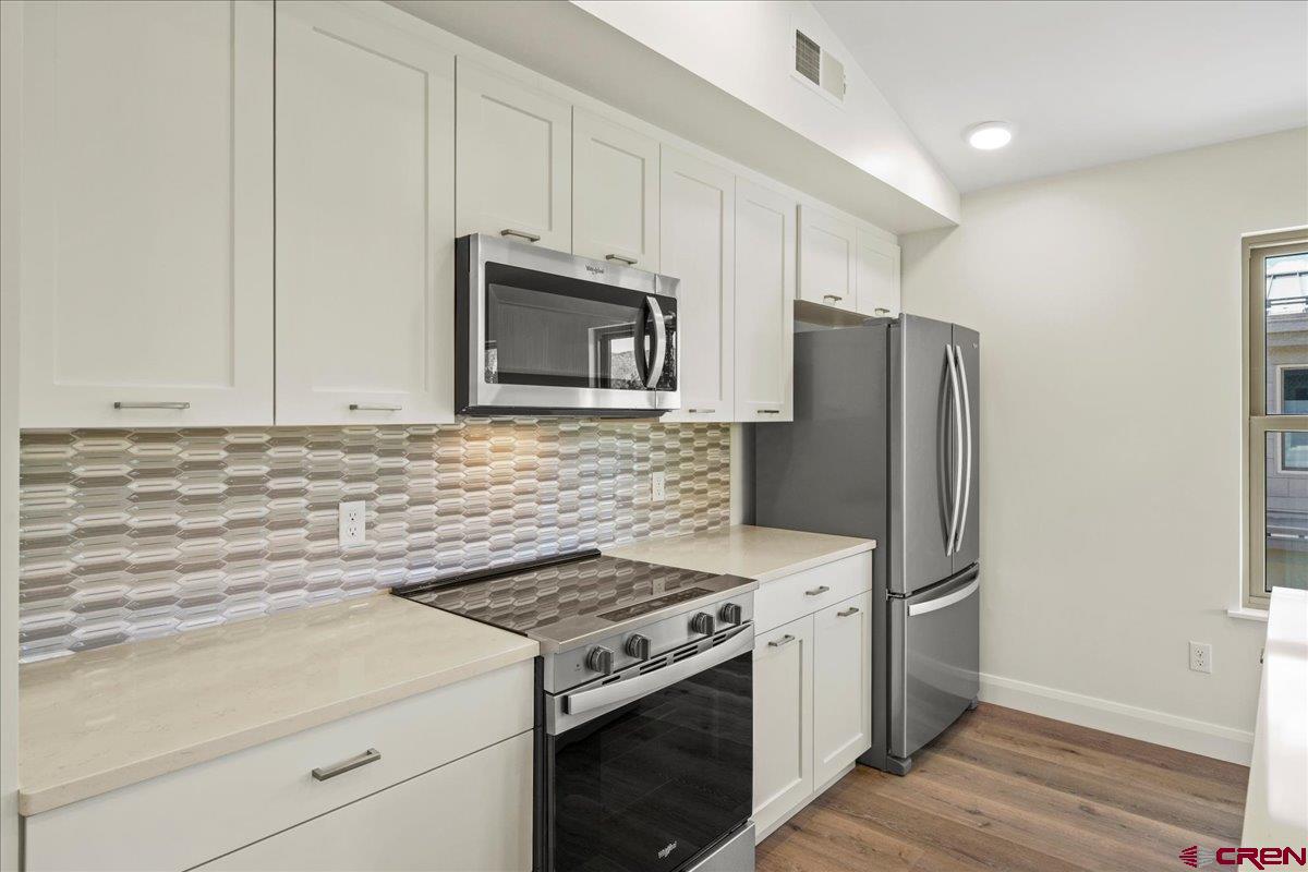 199 Riverfront Lane, Unit 200 Ridgway, CO 81432 - Photo 15 of 28 a kitchen with stainless steel appliances white cabinets and a stove top oven