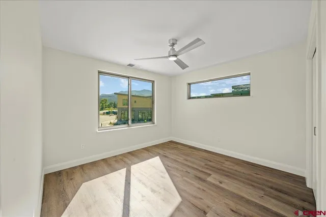 a view of a bedroom with wooden floor and windows