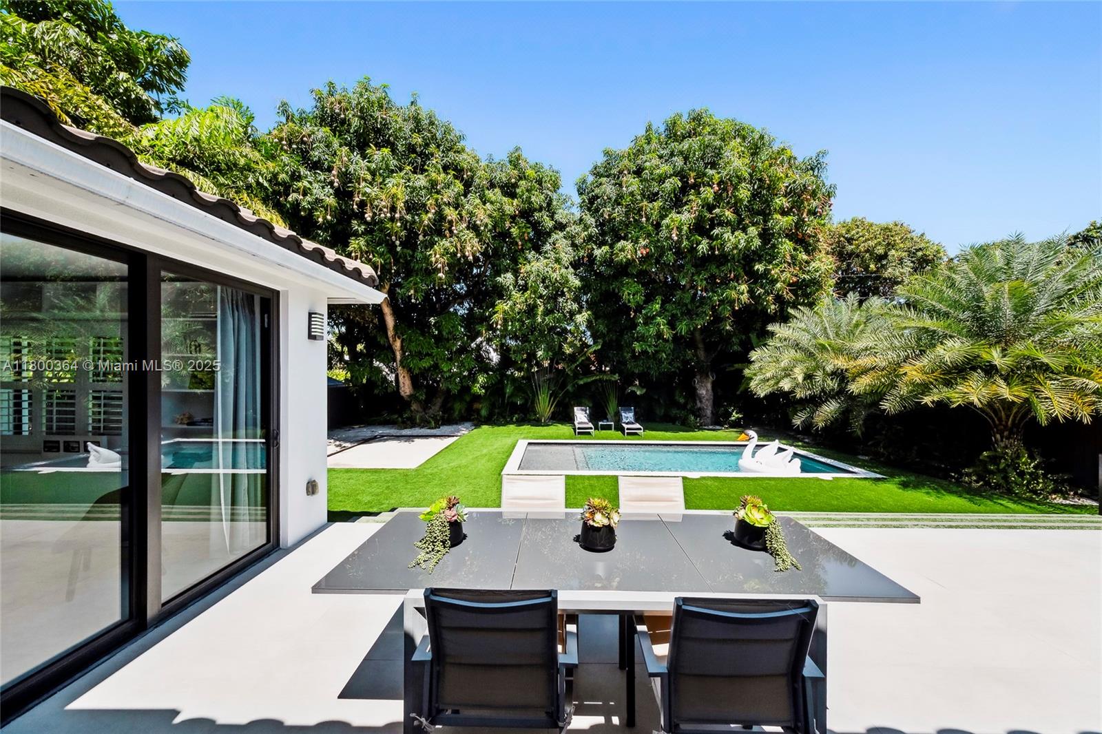 4275 Prairie Avenue Miami Beach, FL 33140 - Photo 26 of 61 a view of backyard with swimming pool and table and chairs under an umbrella