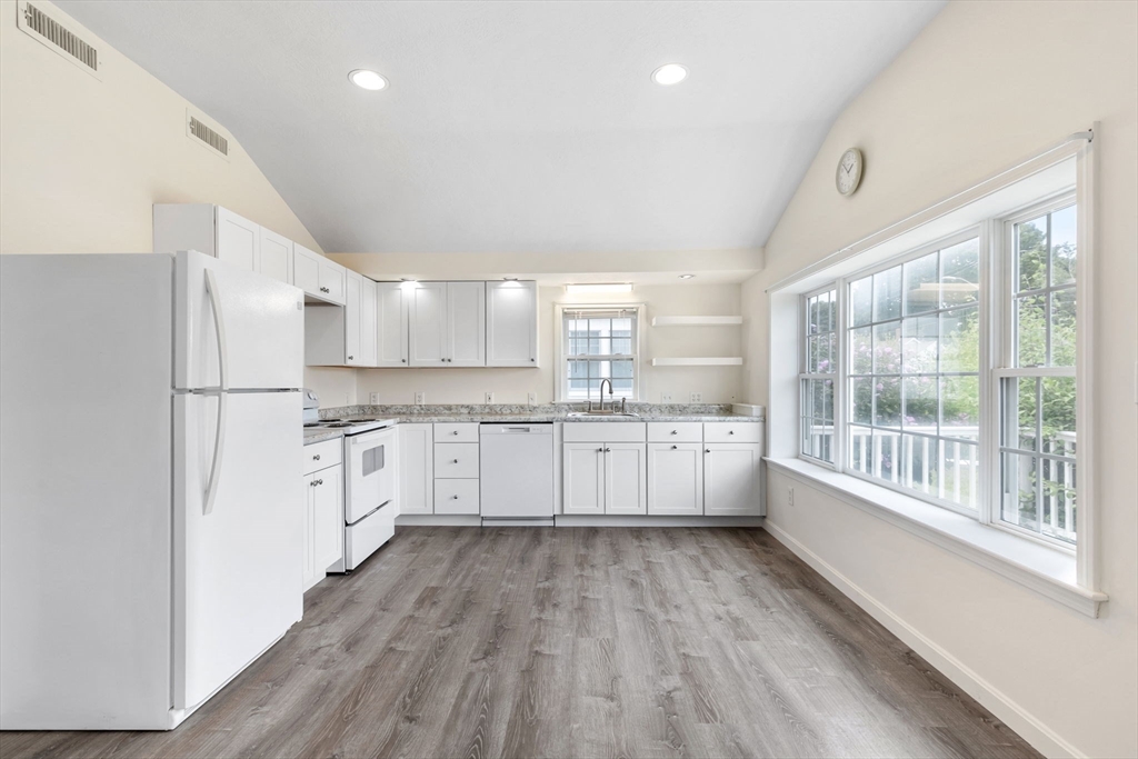 9 Foam Road Scituate, MA 02066 - Photo 6 of 19 a large white kitchen with a refrigerator a sink dishwasher a stove and white cabinets with wooden floor