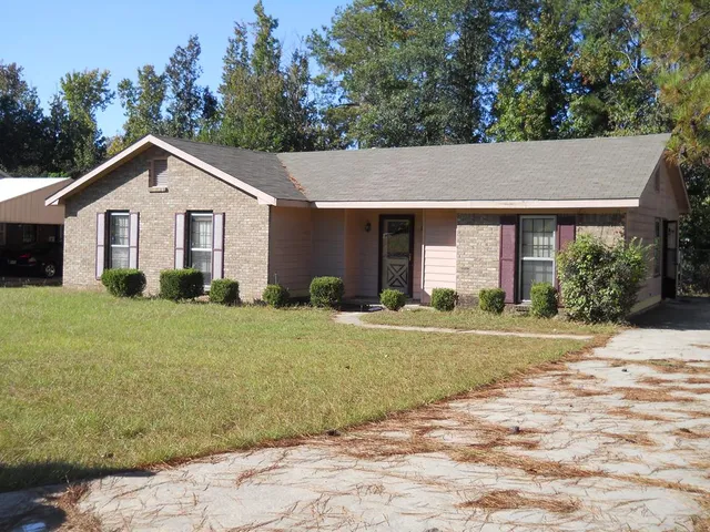 a view of a house with yard and trees in the background