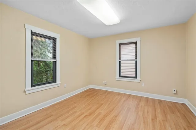 an empty room with wooden floor and windows