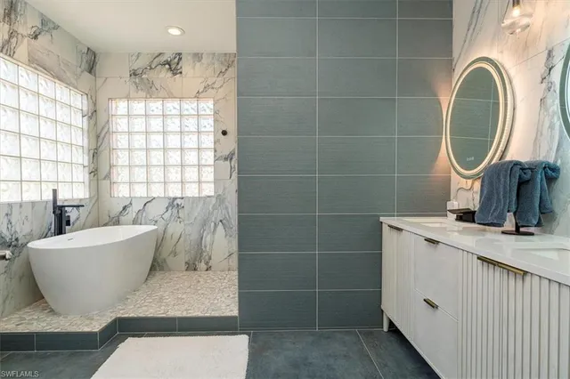 a bathroom with a granite countertop sink a mirror and a bathtub