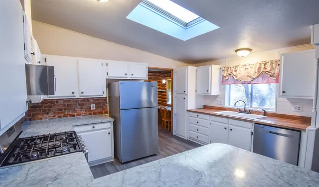 a kitchen with a sink stainless steel appliances a counter top space and cabinets