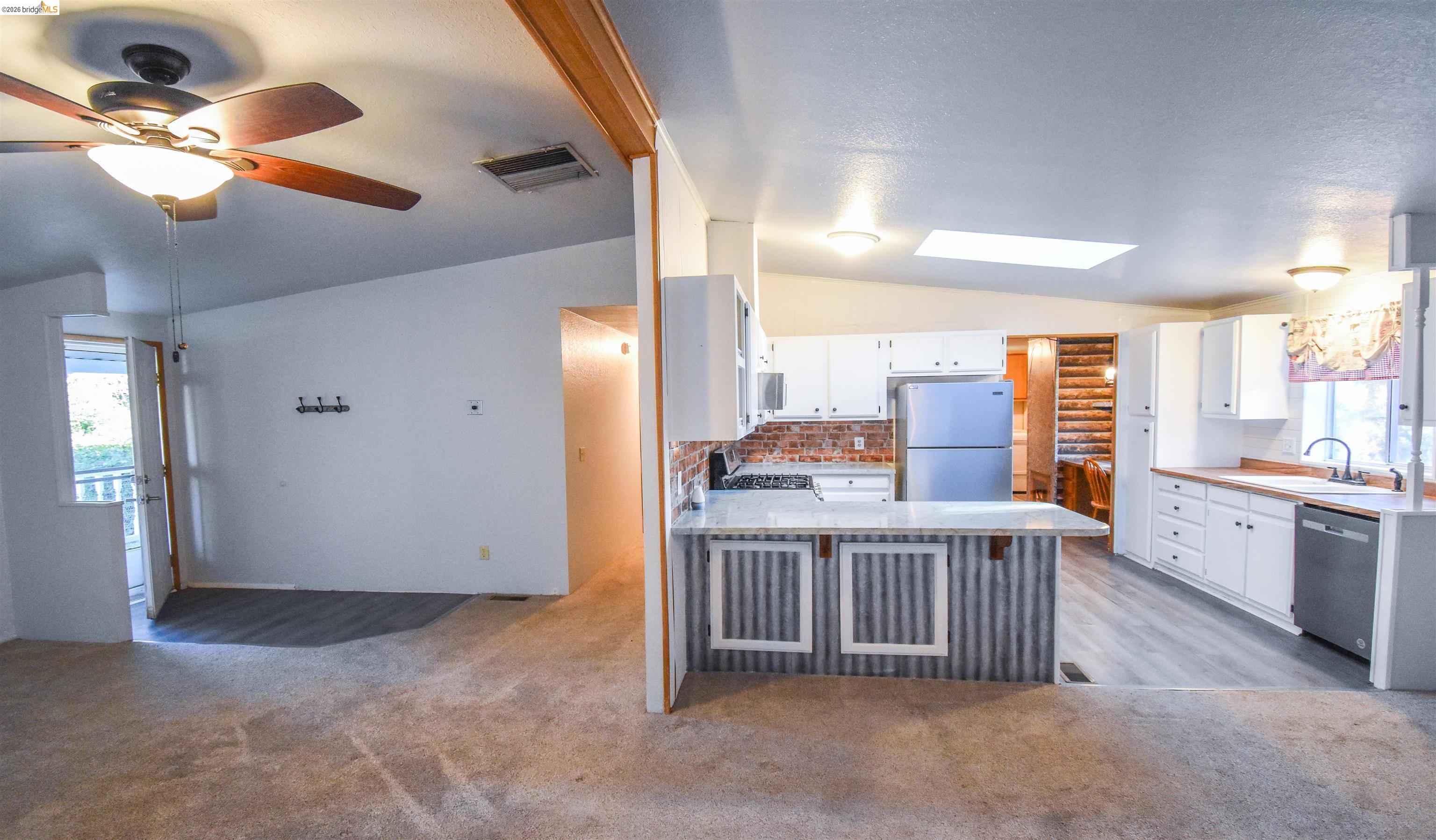 18330 Wards Ferry, Unit 32 Sonora, CA 95370 - Photo 19 of 36 Kitchen with plenty of natural light, white cabinets, vaulted ceiling, a skylight, and appliances with stainless steel finishes