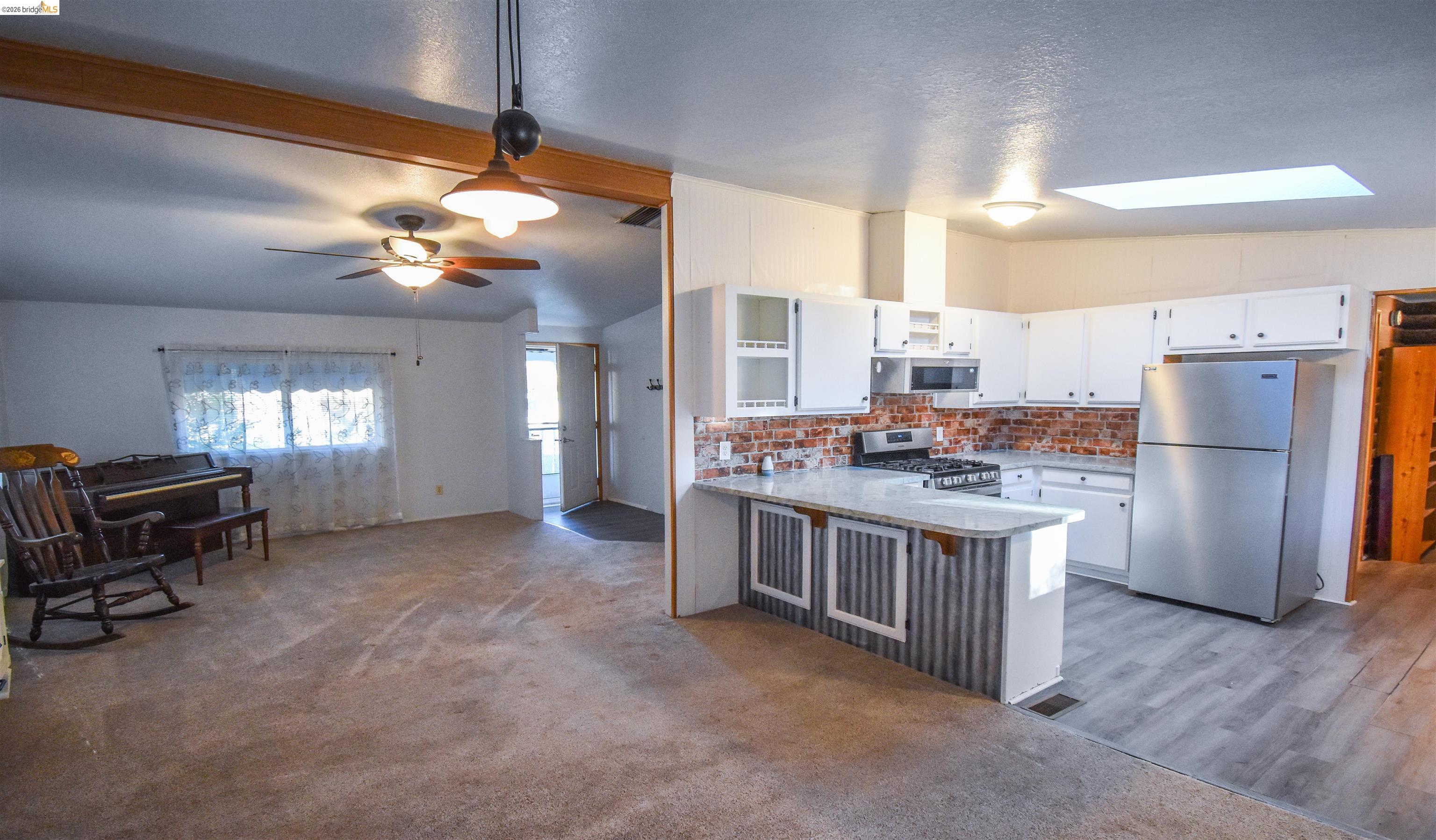 18330 Wards Ferry, Unit 32 Sonora, CA 95370 - Photo 20 of 36 Kitchen with white cabinetry, appliances with stainless steel finishes, decorative light fixtures, a kitchen breakfast bar, and a skylight
