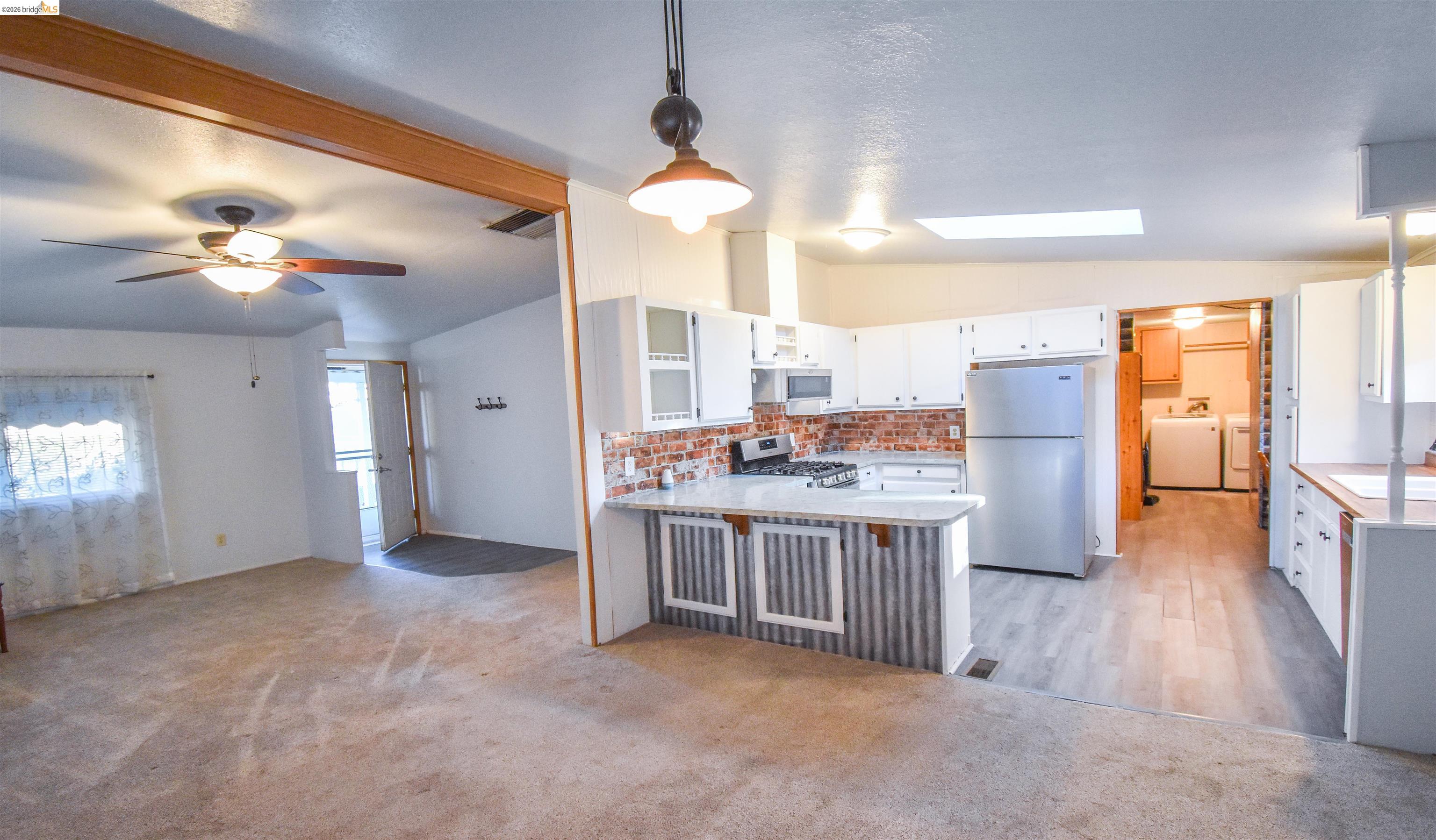 18330 Wards Ferry, Unit 32 Sonora, CA 95370 - Photo 28 of 36 Kitchen with white cabinets, lofted ceiling, stainless steel appliances, hanging light fixtures, and a peninsula