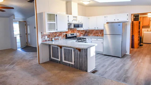 a kitchen with stainless steel appliances granite countertop a refrigerator a stove and a sink