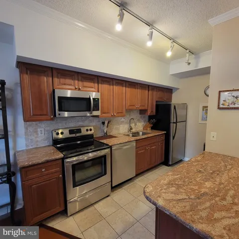 a kitchen with stainless steel appliances granite countertop a stove refrigerator sink and microwave