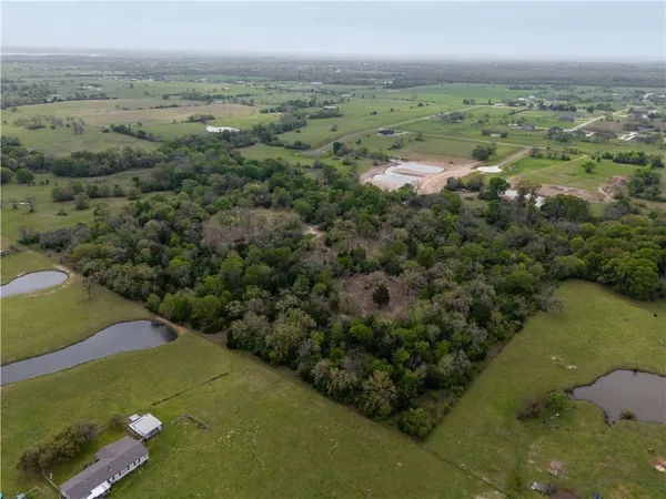 an aerial view of a houses with outdoor space and trees all around