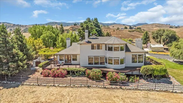a view of a big house with a big yard plants and large trees
