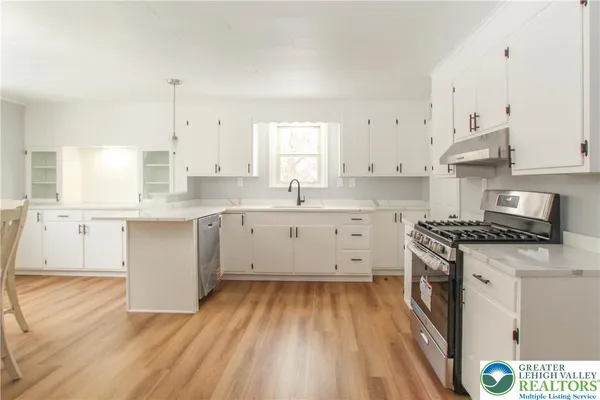 a kitchen with stainless steel appliances granite countertop a stove a sink and white cabinets