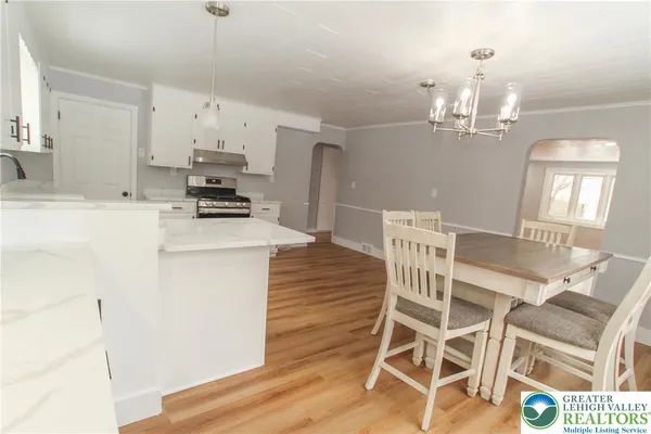 a kitchen with stainless steel appliances kitchen island granite countertop a dining table chairs refrigerator and sink