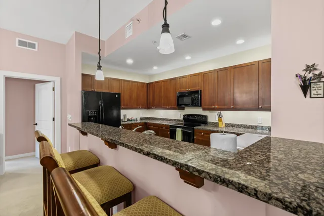 a kitchen with stainless steel appliances kitchen island granite countertop a refrigerator a sink a stove and a refrigerator with wooden floor