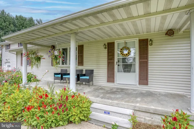 a front view of a house with chairs and flower plants