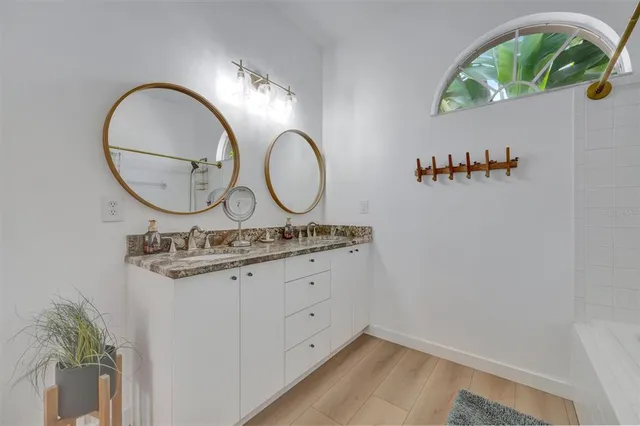a bathroom with a granite countertop double vanity sink and a mirror
