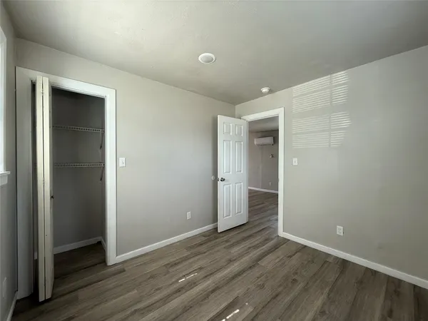 a view of an empty room with wooden floor and closet