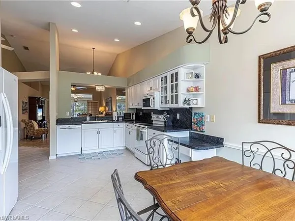 a kitchen with stainless steel appliances kitchen island granite countertop a refrigerator a stove a sink dishwasher and white cabinets with wooden floor