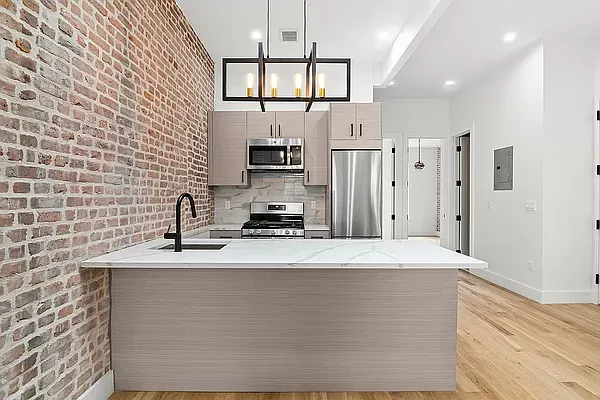 a kitchen with stainless steel appliances granite countertop a sink a stove a refrigerator a microwave oven with white cabinets