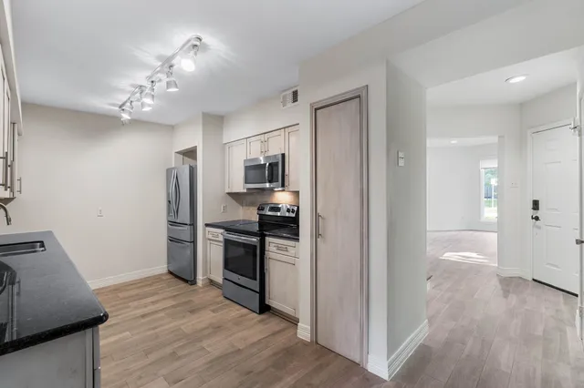 a view of a kitchen with a sink refrigerator and wooden floor