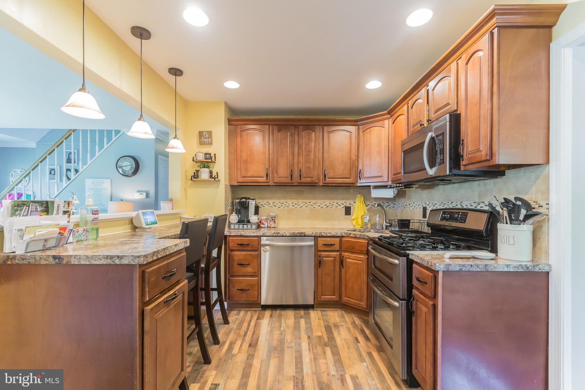 911 Scotia Road Philadelphia, PA 19128 - Photo 10 of 27 a kitchen with stainless steel appliances granite countertop wooden cabinets a stove a sink and a wooden floor
