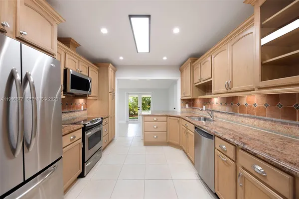 a large kitchen with stainless steel appliances granite countertop a refrigerator and a stove top oven