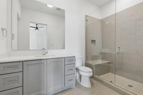 a bathroom with a shower sink vanity mirror and toilet