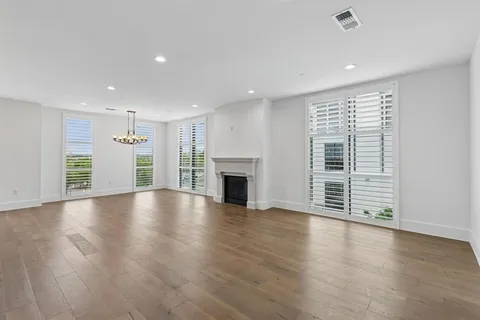 an empty room with wooden floor fireplace and windows
