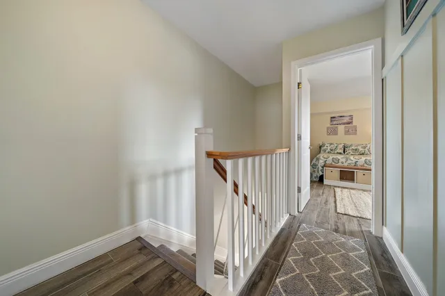 a view of a hallway with wooden floor and a bathroom