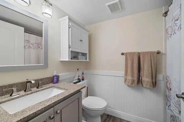 a bathroom with a granite countertop toilet sink and mirror