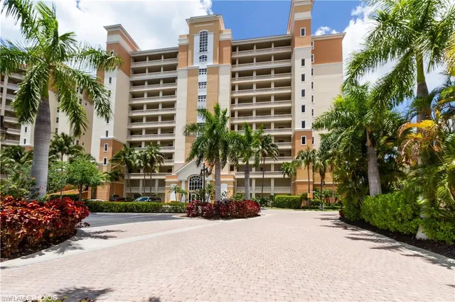 a front view of a multi story building with a yard and fountain in the background