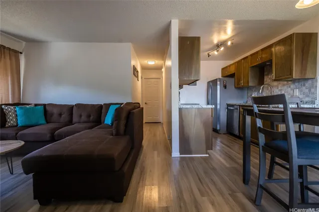 a living room with stainless steel appliances furniture and a wooden floor