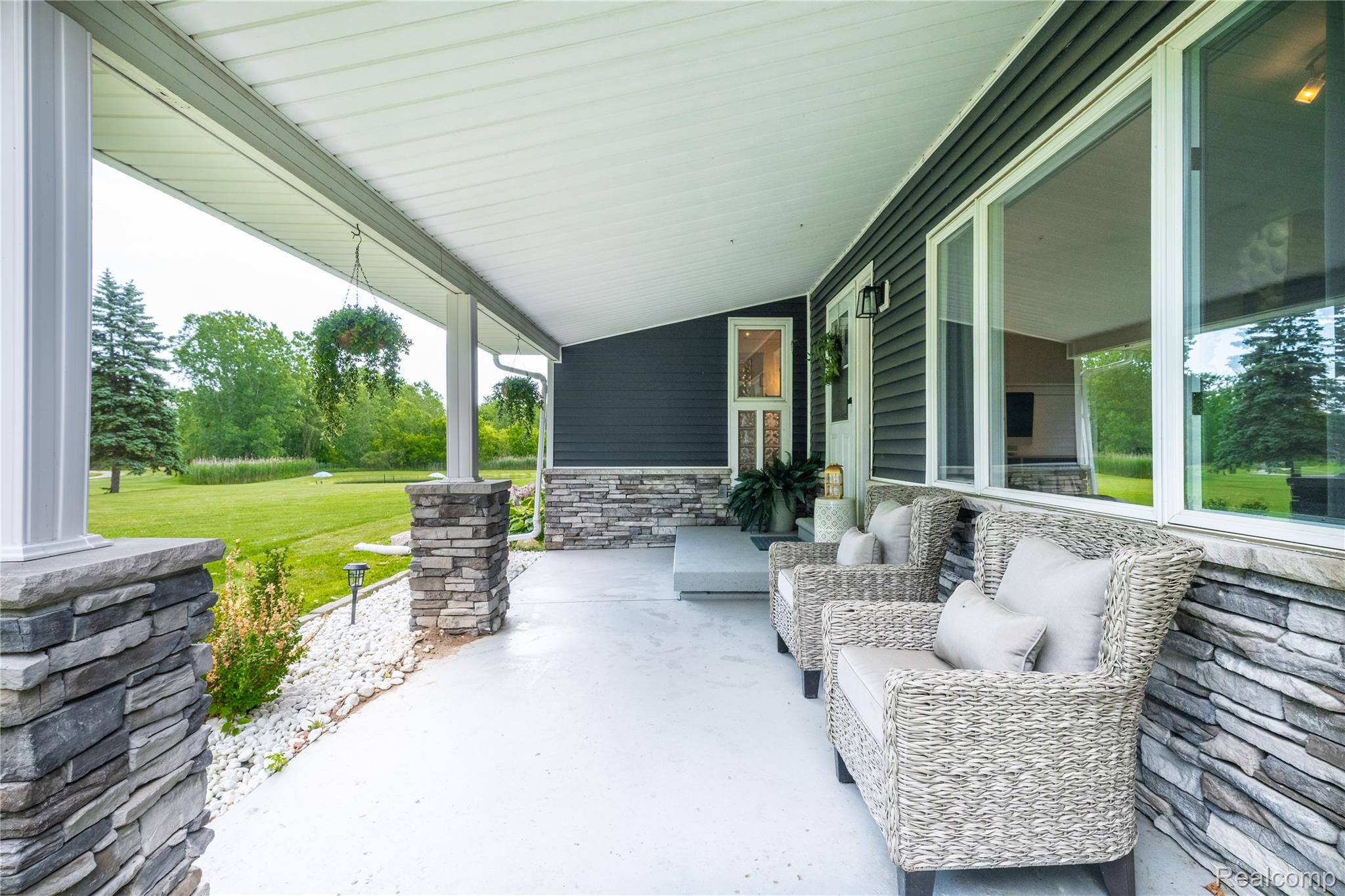 4418 North Gale Road Davison, MI 48423 - Photo 12 of 46 Expansive covered porch featuring a concrete surface, stone veneer accents, large windows, dark siding, and exterior lighting fixtures