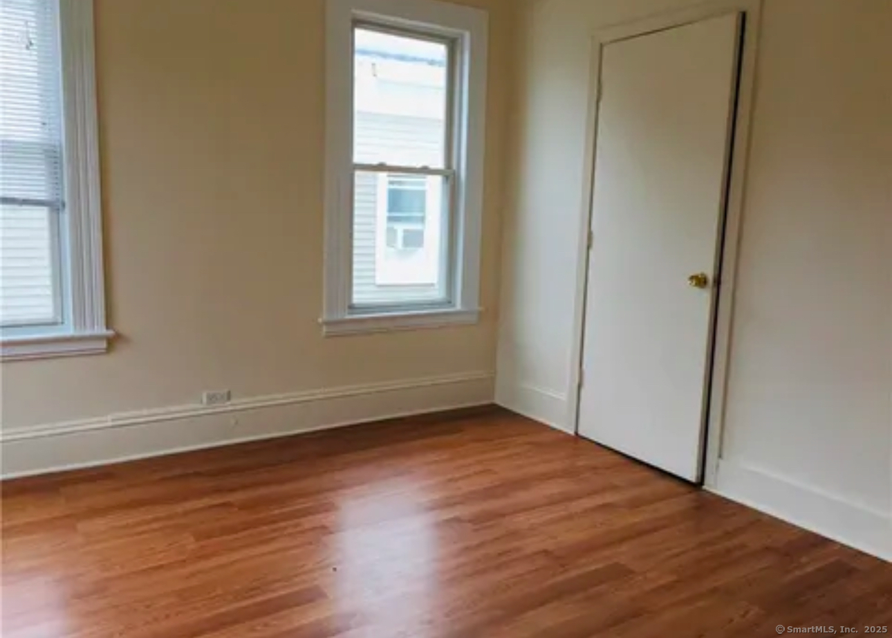 1117 Kossuth Street, Unit 1R Bridgeport, CT 06608 - Photo 1 of 1 an empty room with wooden floor and windows