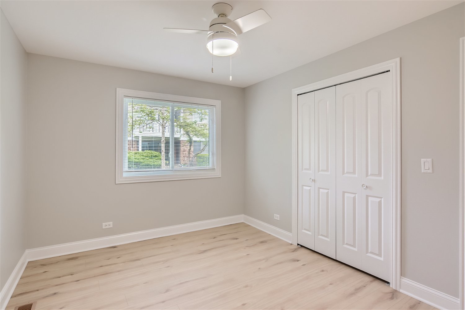 1460 7 Pines Road, Unit A1 Schaumburg, IL 60193 - Photo 10 of 11 an empty room with wooden floor chandelier fan and windows