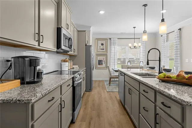 a kitchen with stainless steel appliances granite countertop a sink a stove and a wooden floors