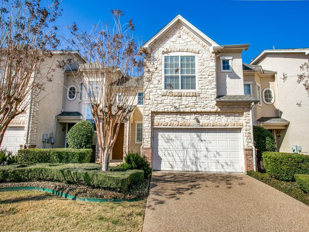 View of front of property with stone siding, driveway, stucco siding, and an attached garage