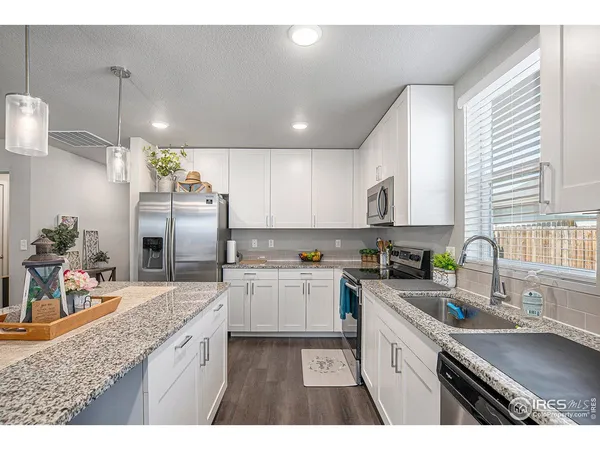 a open kitchen with kitchen island a stove a sink dishwasher and a dining table with wooden floor